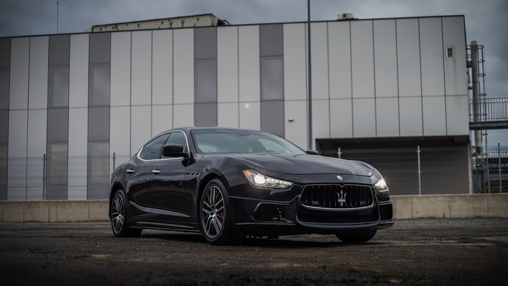 a black masera is parked in front of a building