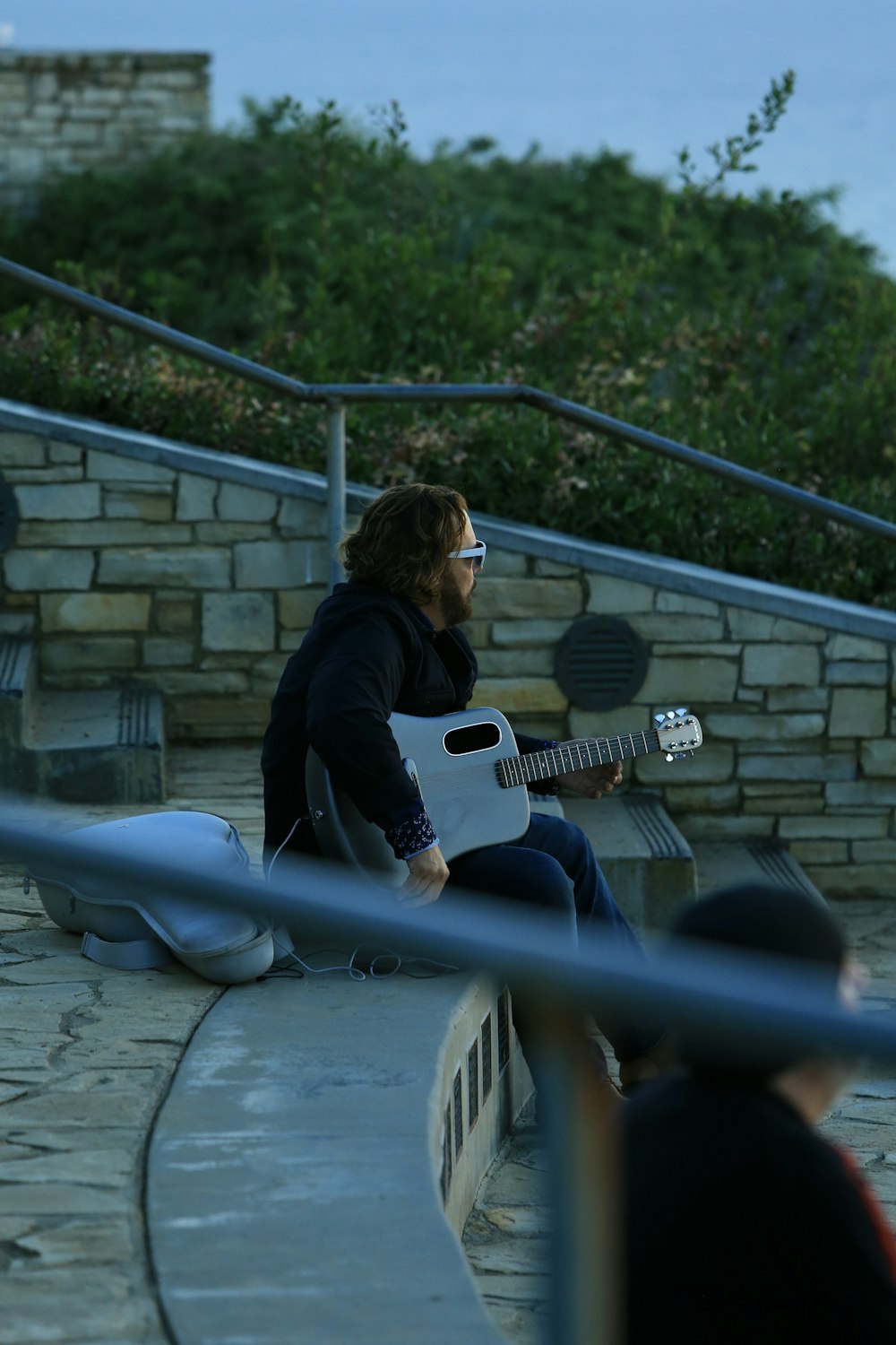 a man sitting on a bench playing a guitar