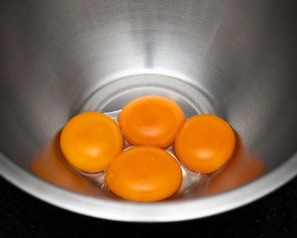 a metal bowl filled with four eggs on top of a counter