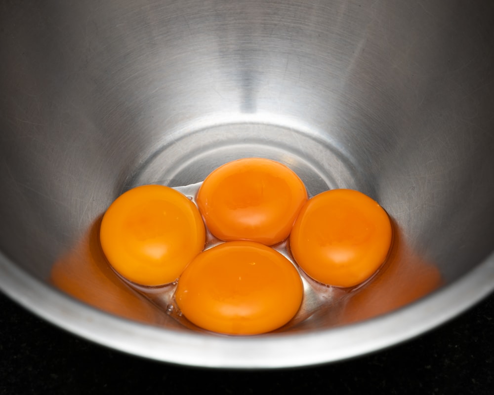 uma tigela de metal cheia com quatro ovos em cima de um balcão