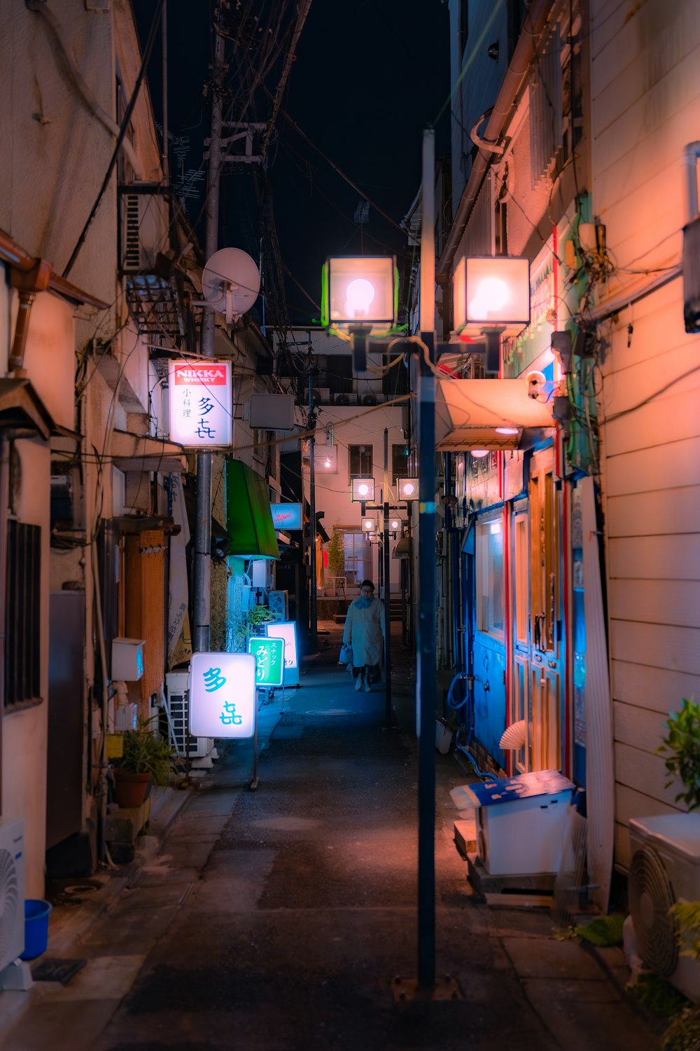 a narrow alley way at night with lights on