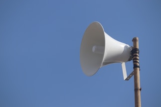a white bullhorn on top of a wooden pole