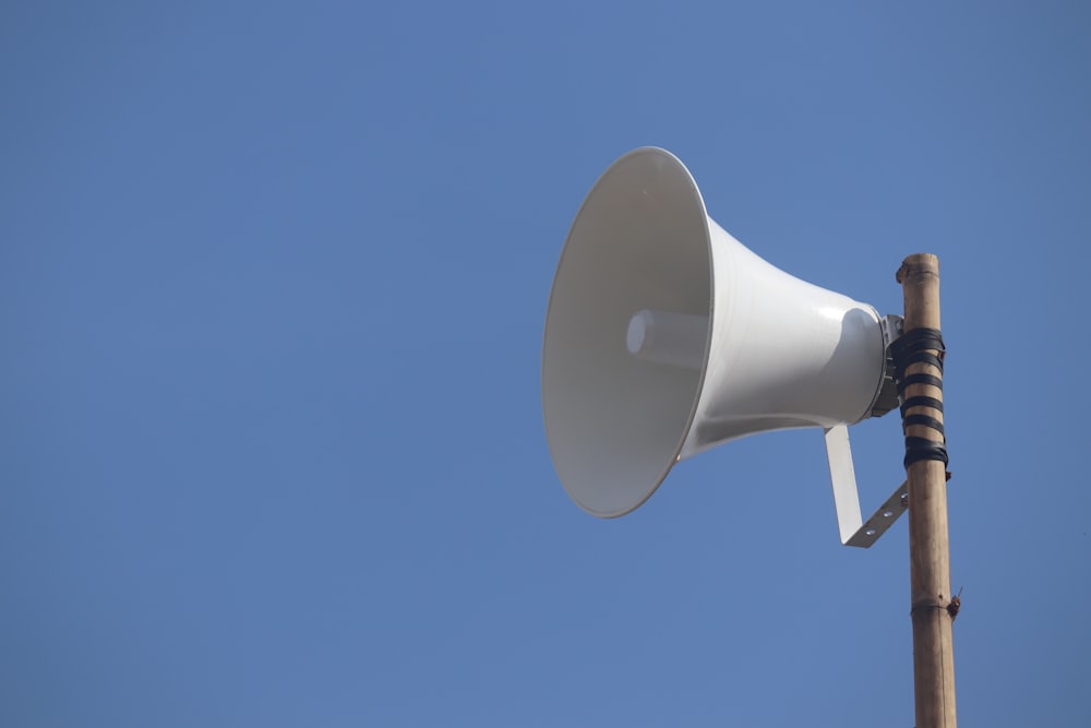 a white bullhorn on top of a wooden pole