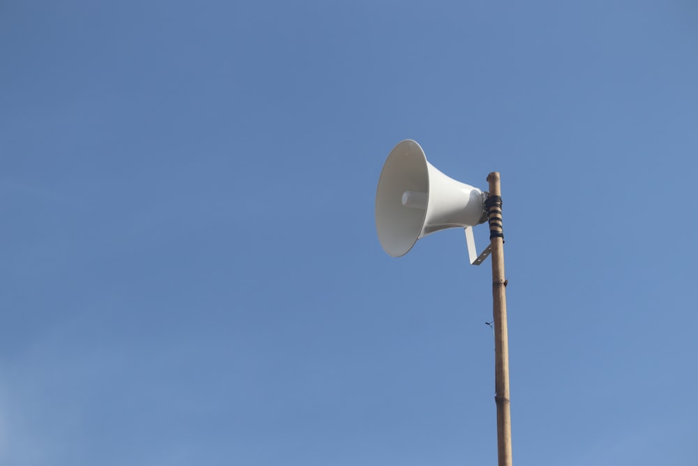 a white bullhorn on top of a wooden pole
