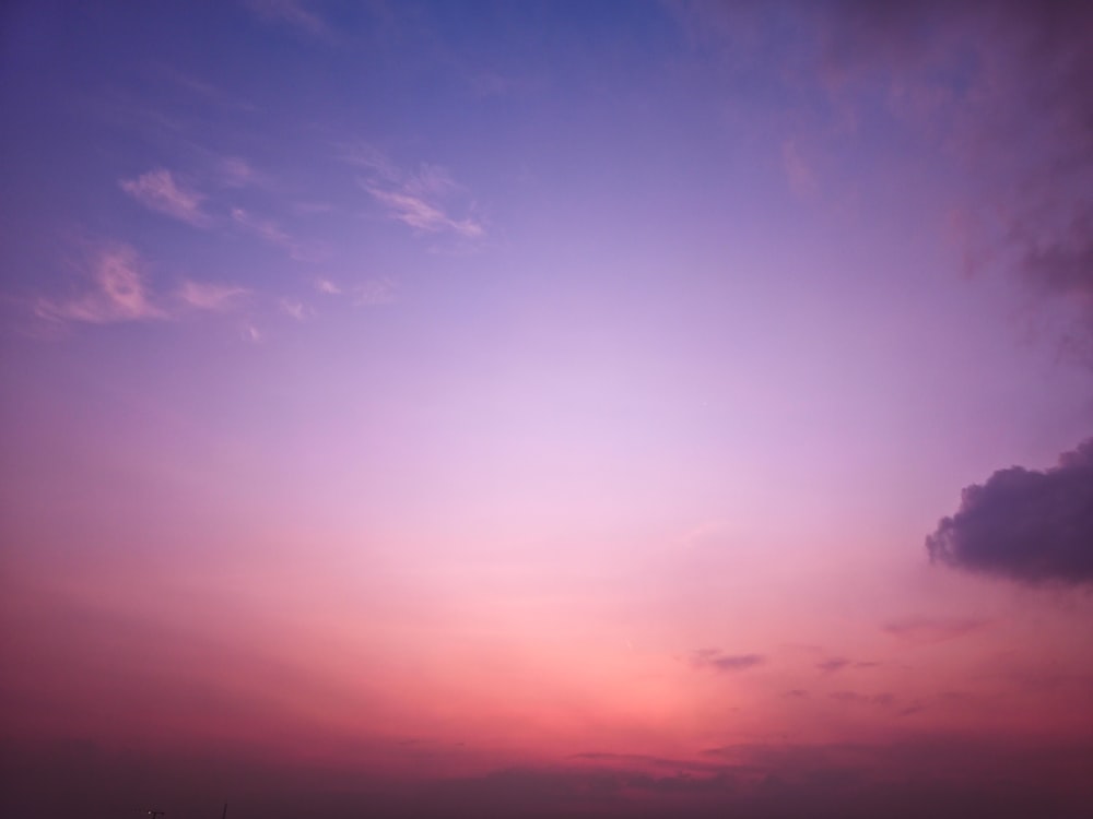 the sky is pink and purple with a few clouds