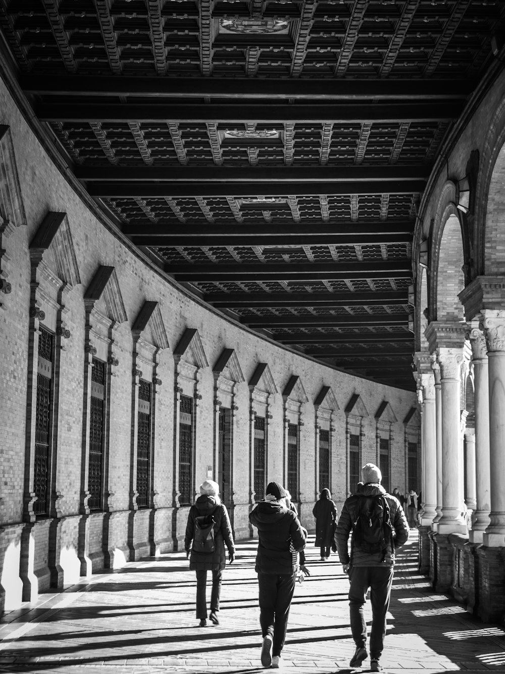 black and white photograph of people walking under a bridge