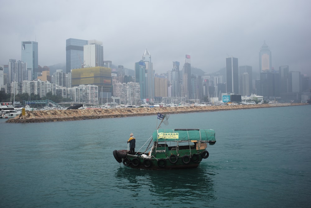 a man standing on the back of a boat in the water