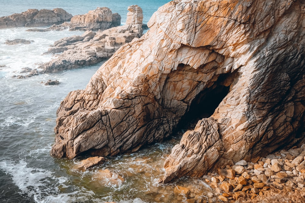 una grande formazione rocciosa seduta in cima a una spiaggia vicino all'oceano