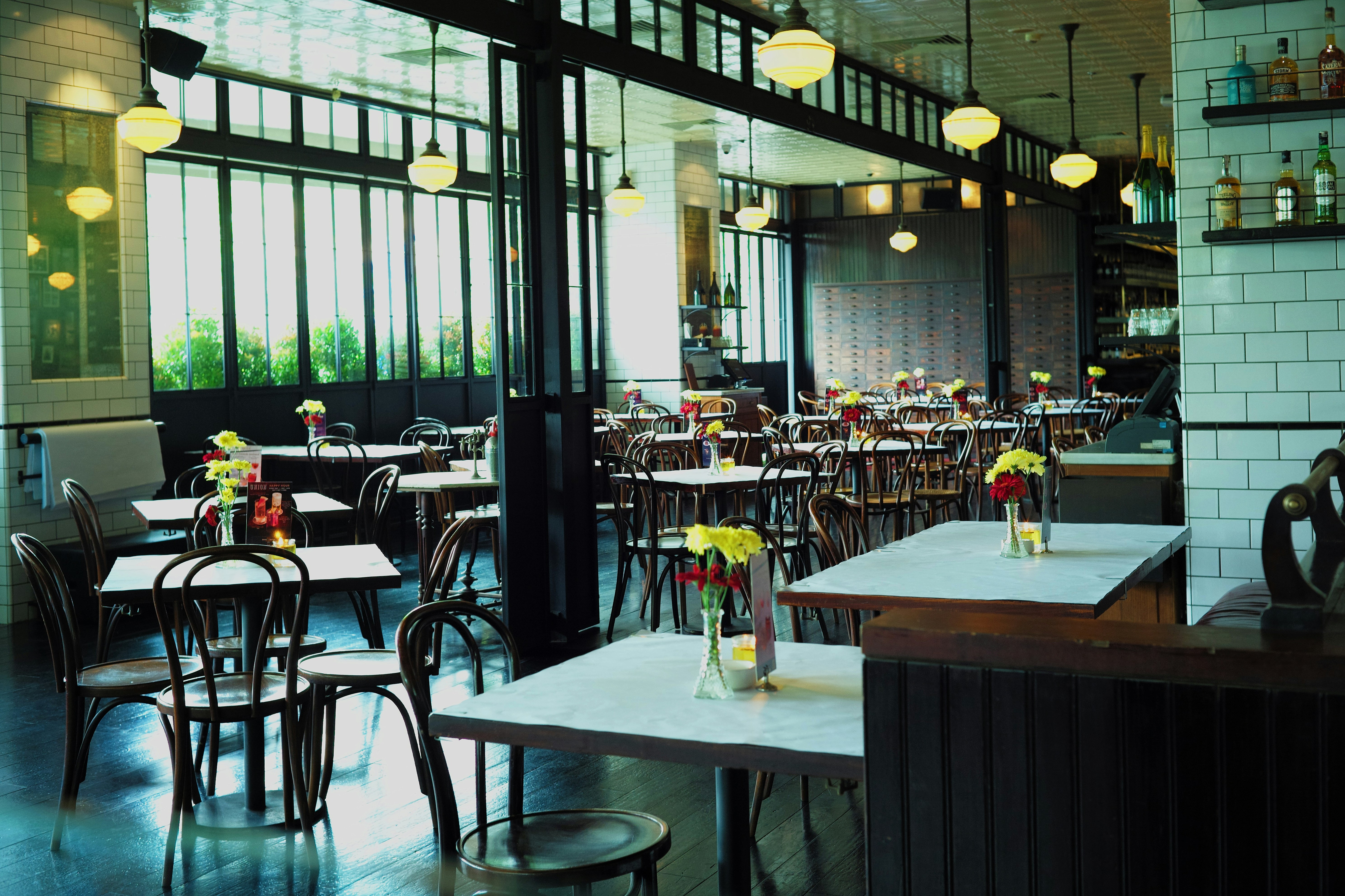 Restaurant interior with warm dim lighting, empty tables with candles, cosy atmosphere