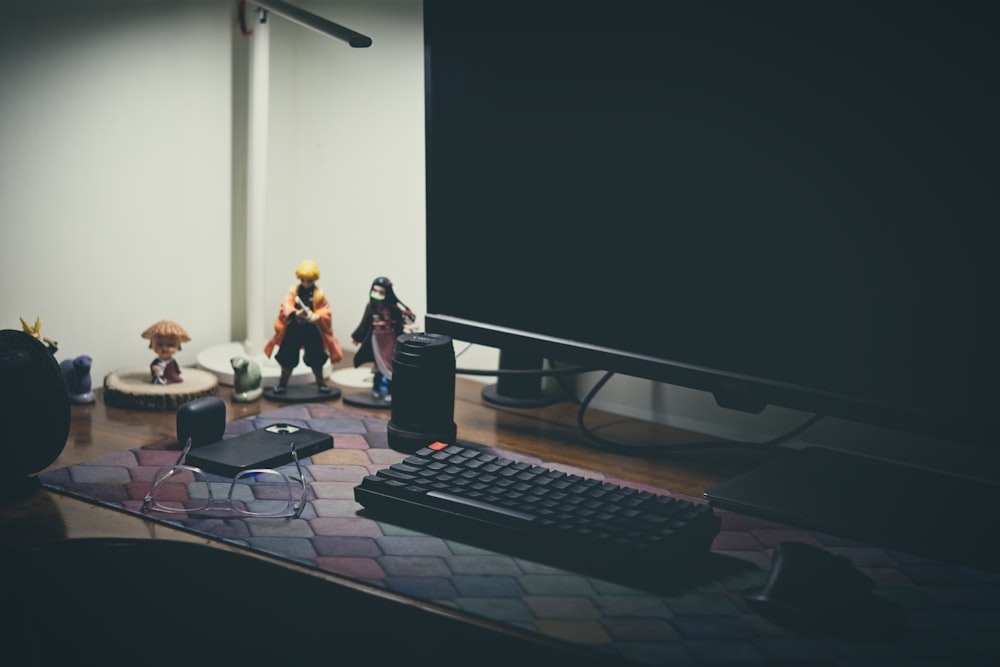 a desk with a keyboard, mouse, and figurines on it