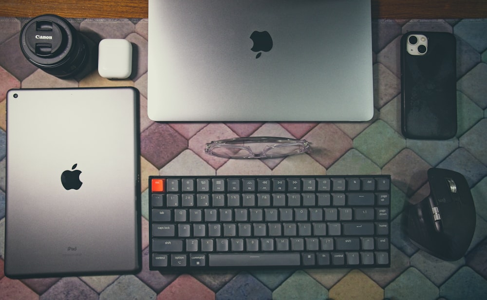 a laptop, keyboard, mouse, and other electronics on a table