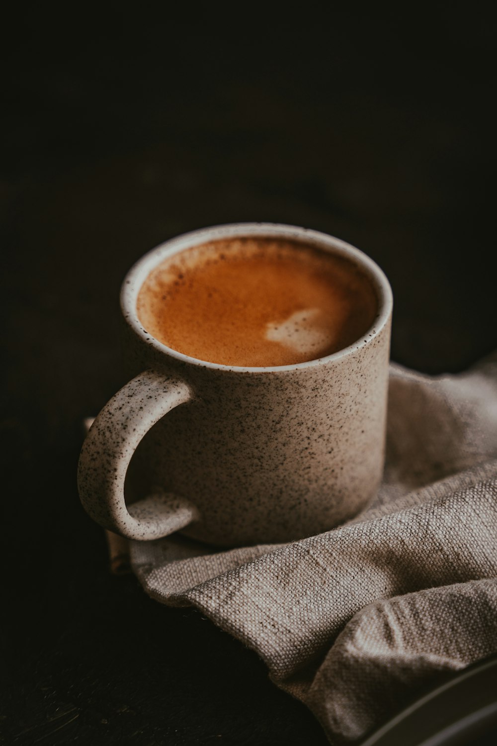 a cup of coffee sitting on top of a cloth