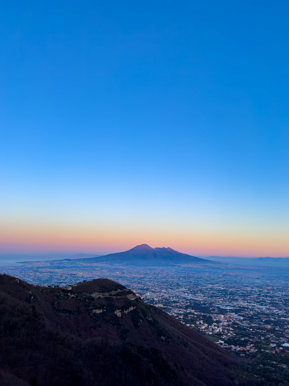a view of a city and a mountain at sunset