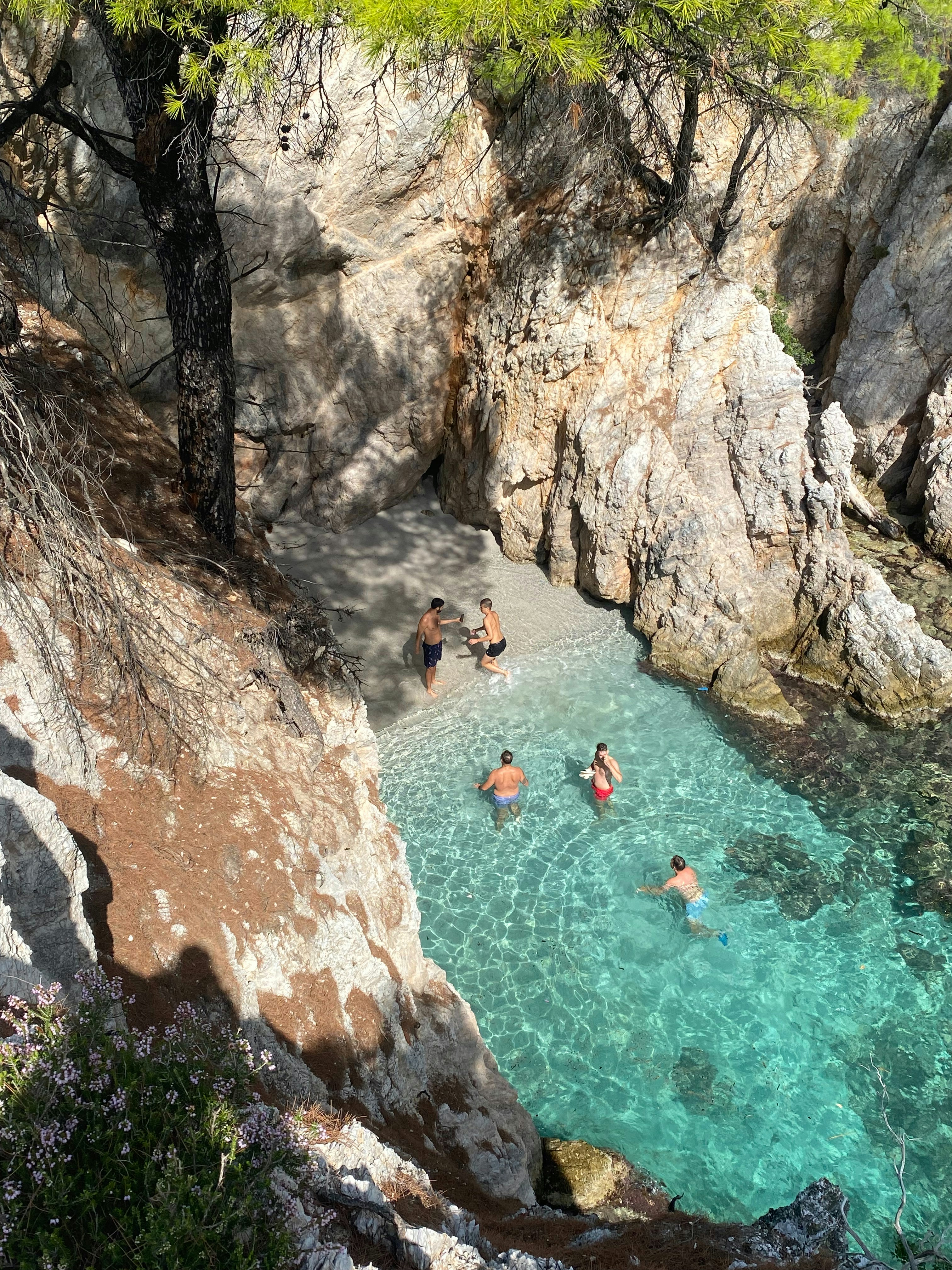 a group of people swimming in a pool next to a cliff