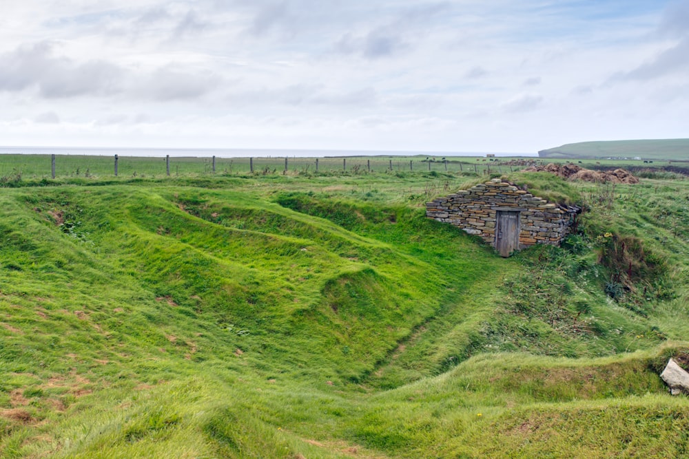 a grassy area with a small building on top of it