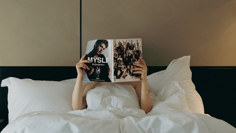 a person laying in bed reading a book