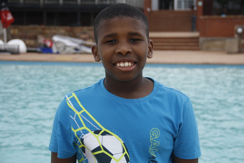 a young boy standing in front of a swimming pool