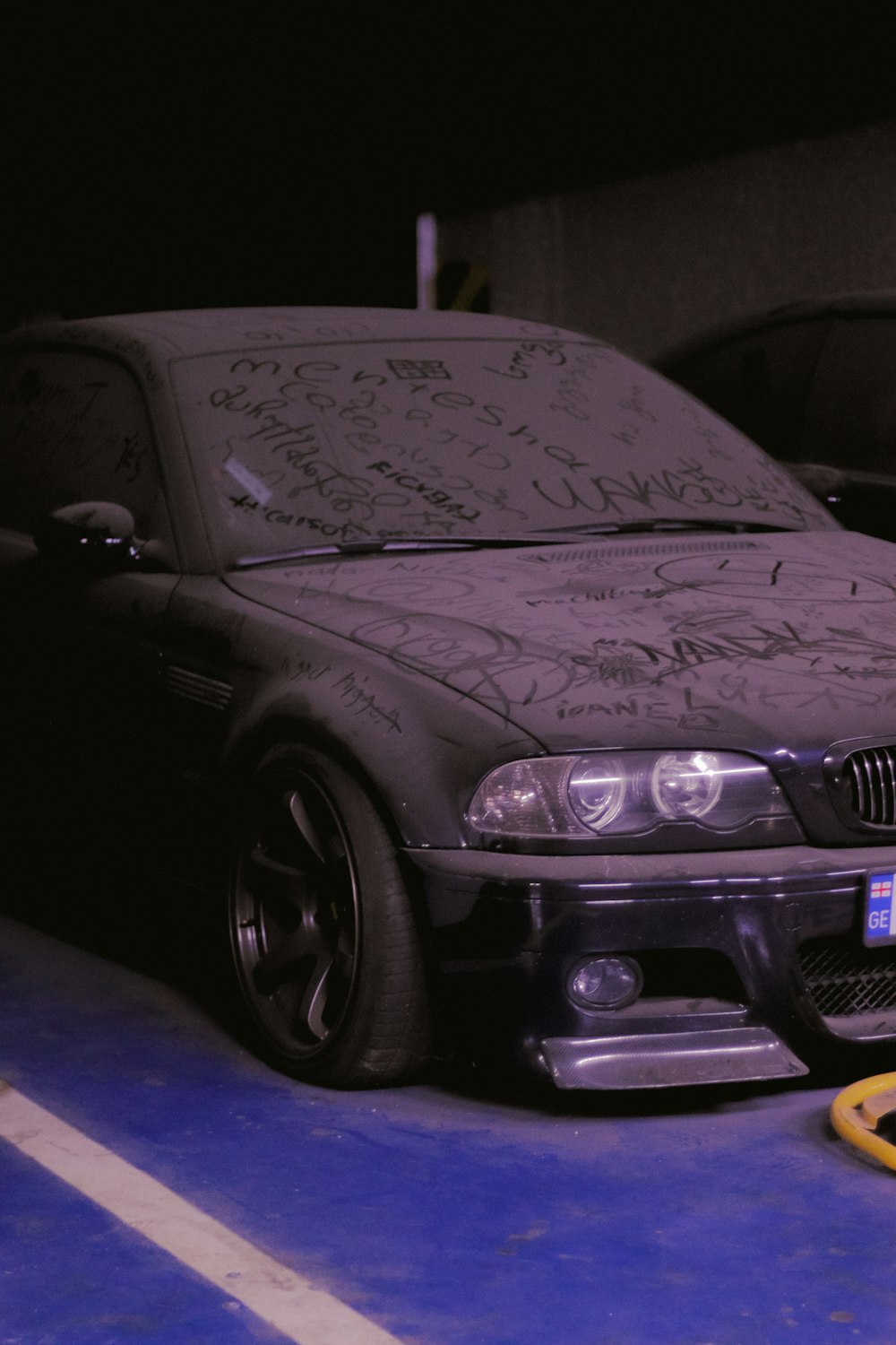 a car parked in a parking lot with graffiti on it