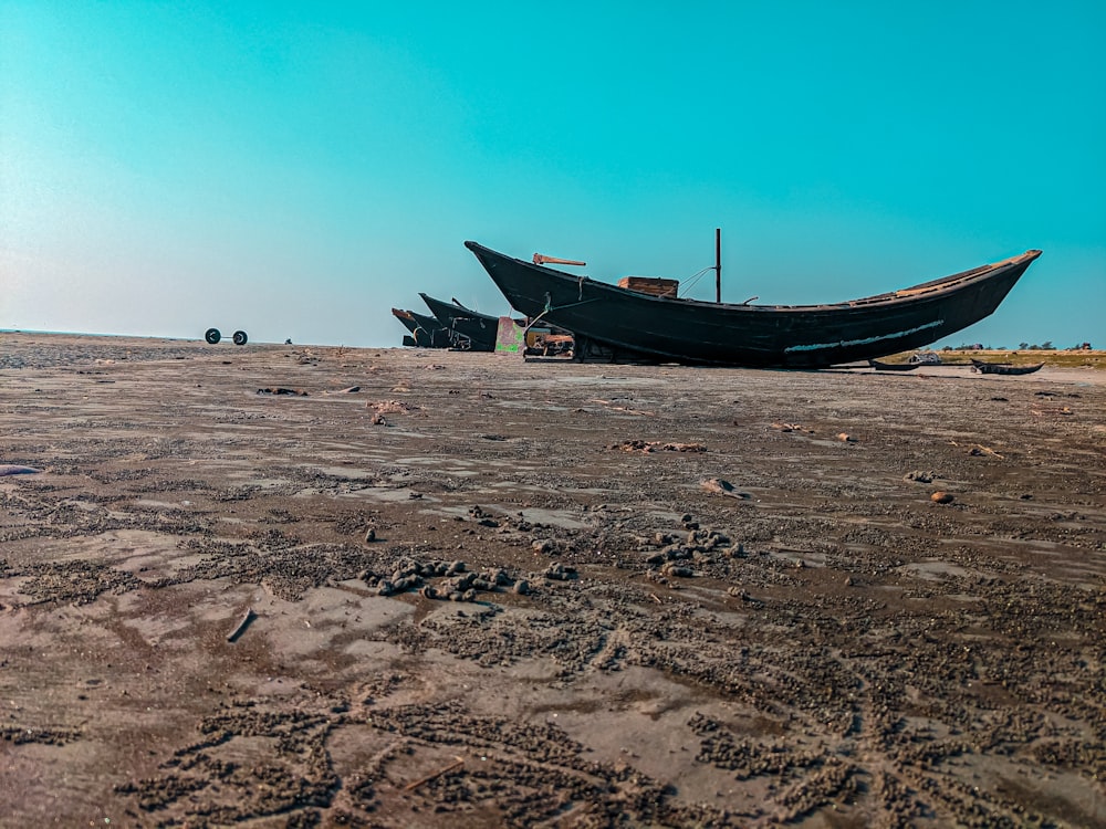 a couple of boats sitting on top of a sandy beach