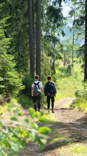 two people walking down a trail in the woods