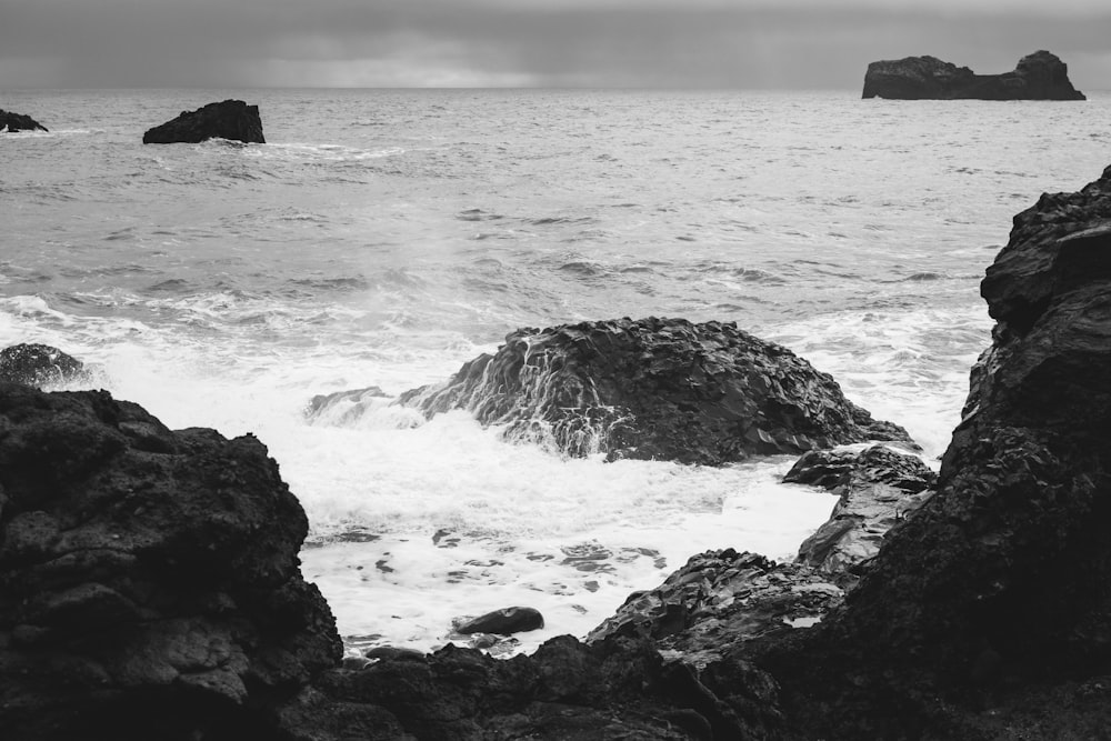 a black and white photo of the ocean and rocks