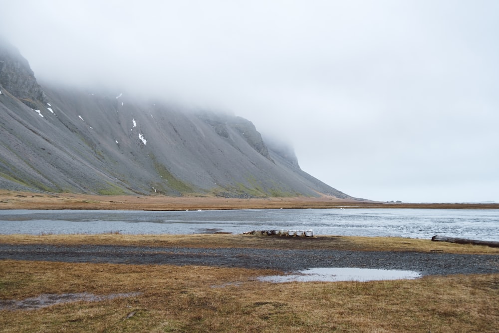 a body of water surrounded by mountains and grass