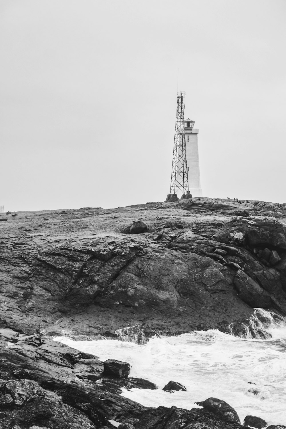 바위가 많은 해안에 있는 등대의 흑백 사진