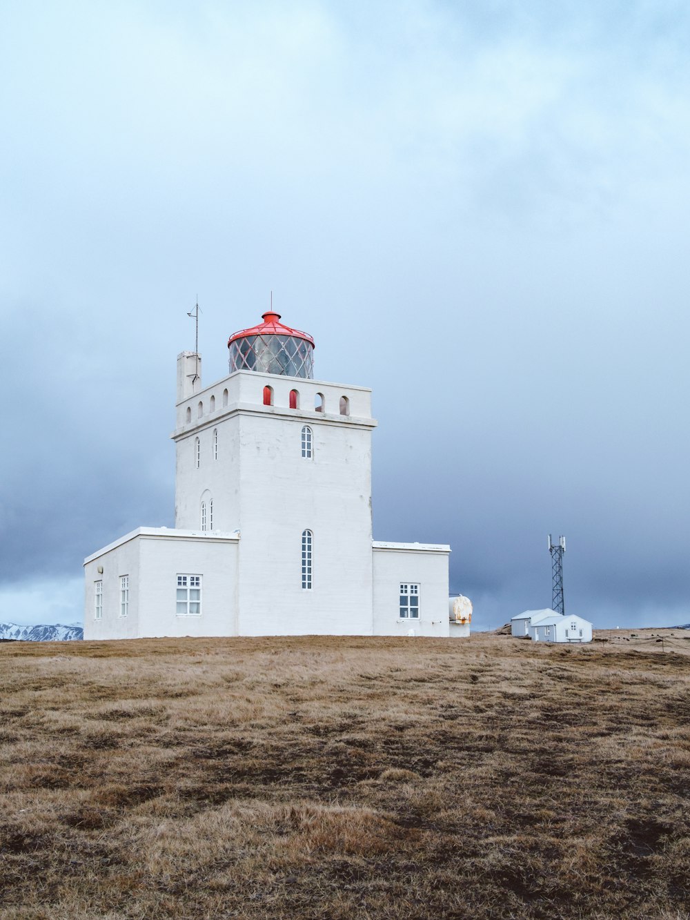 a large white building sitting on top of a dry grass field