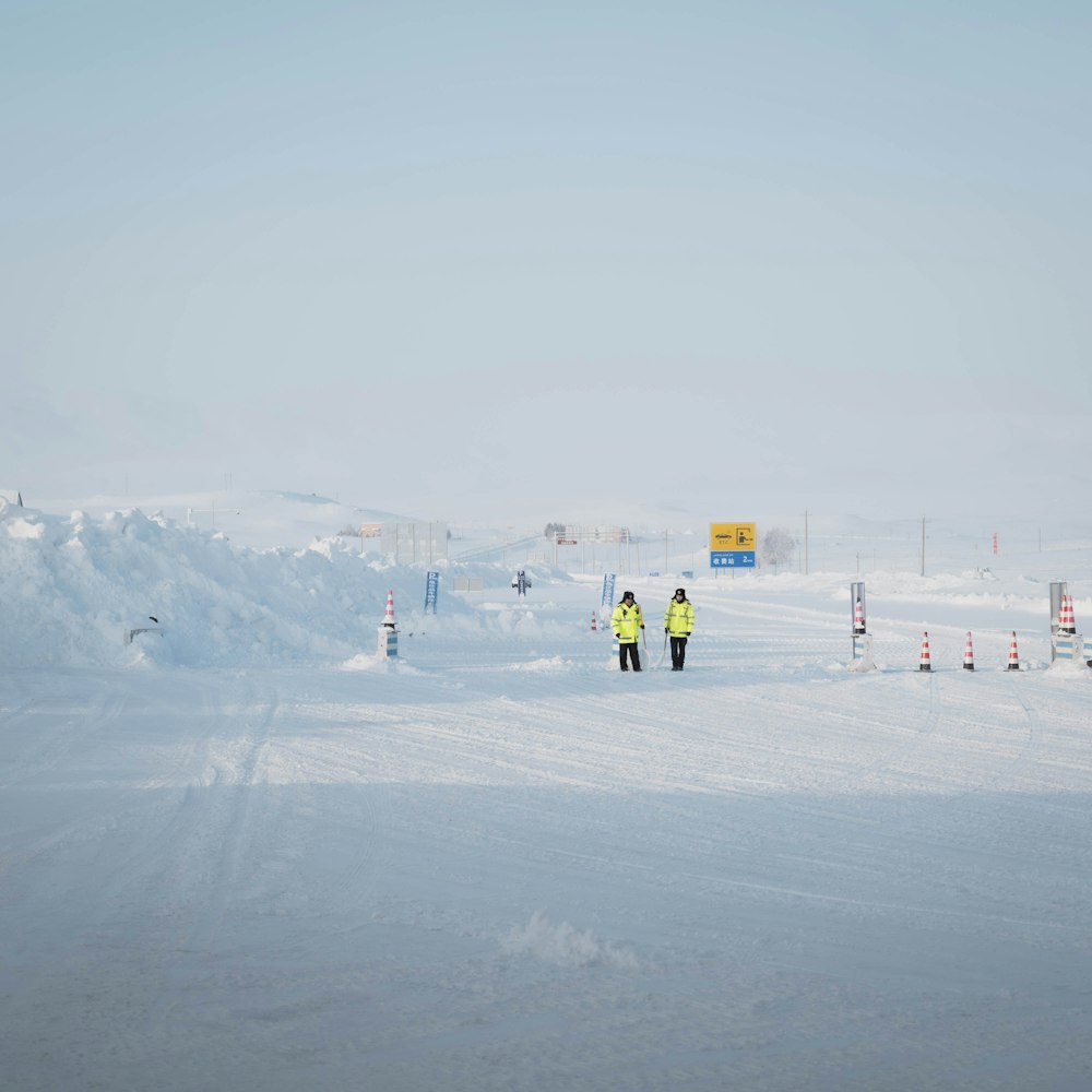 a couple of people walking across a snow covered field