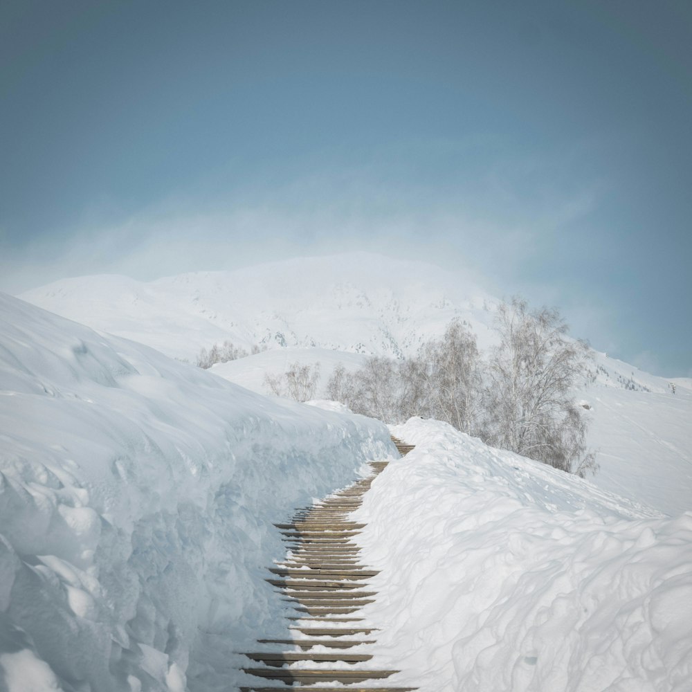 a long wooden path in the middle of a snow covered mountain