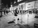 a man standing on a sidewalk with a guitar
