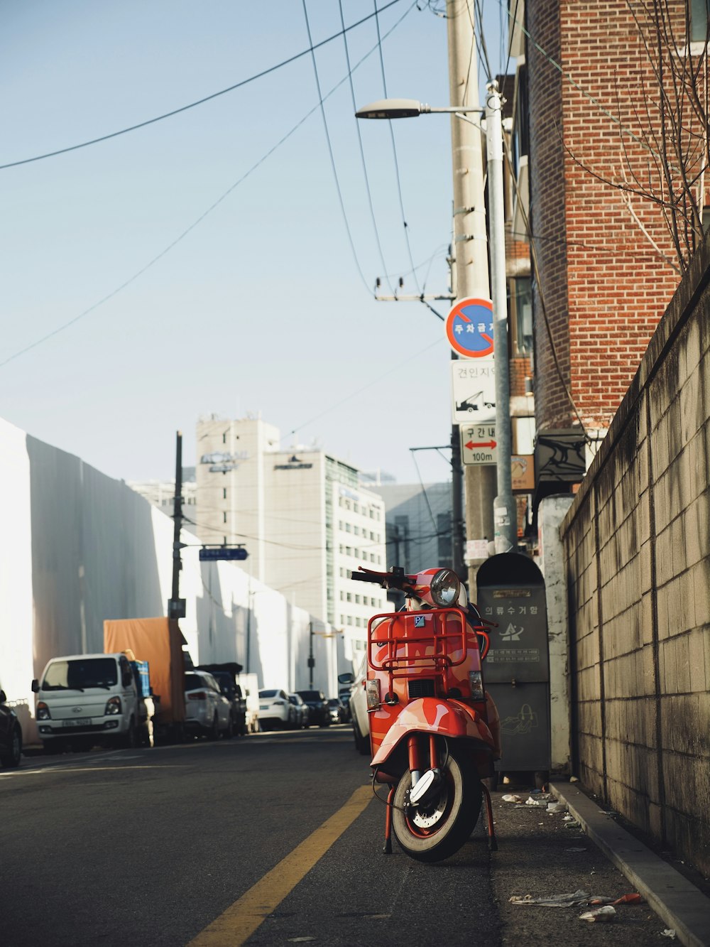 a red scooter parked on the side of a street