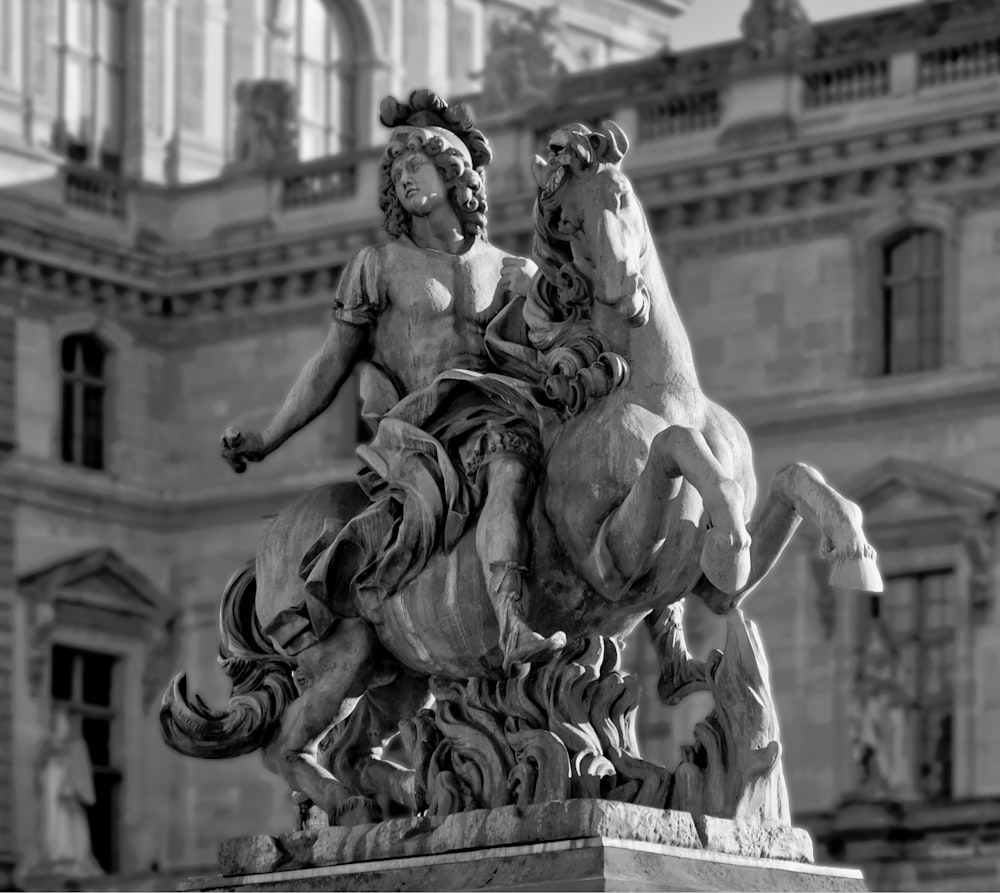a statue of two women riding horses in front of a building