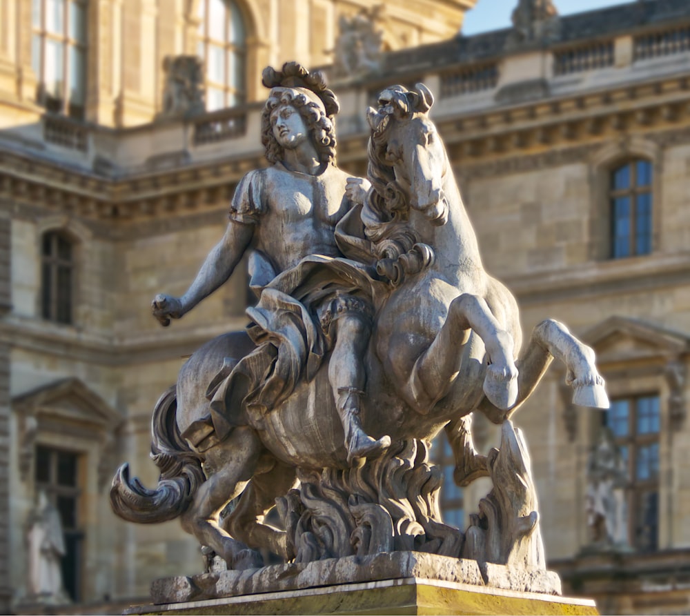 a statue of a woman riding a horse in front of a building