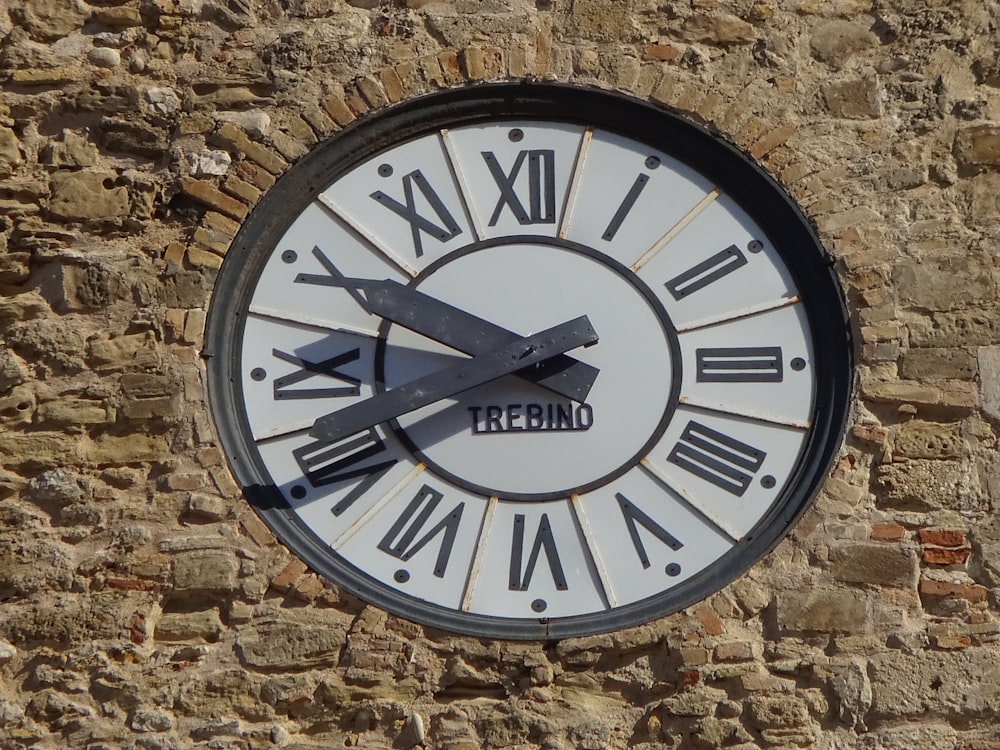 a clock with roman numerals on a stone wall