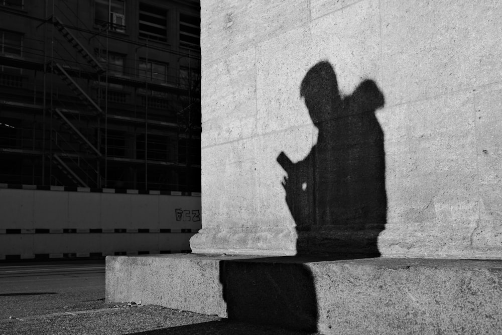 l'ombra di una persona che tiene in mano un telefono cellulare