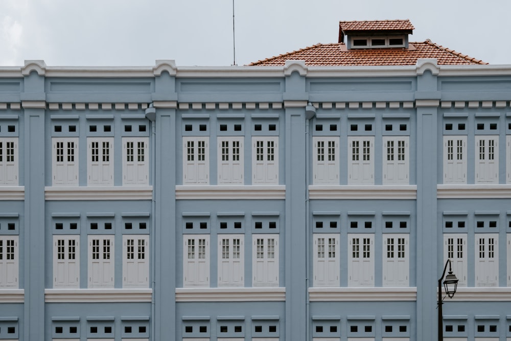 a tall blue building with white windows and a red roof