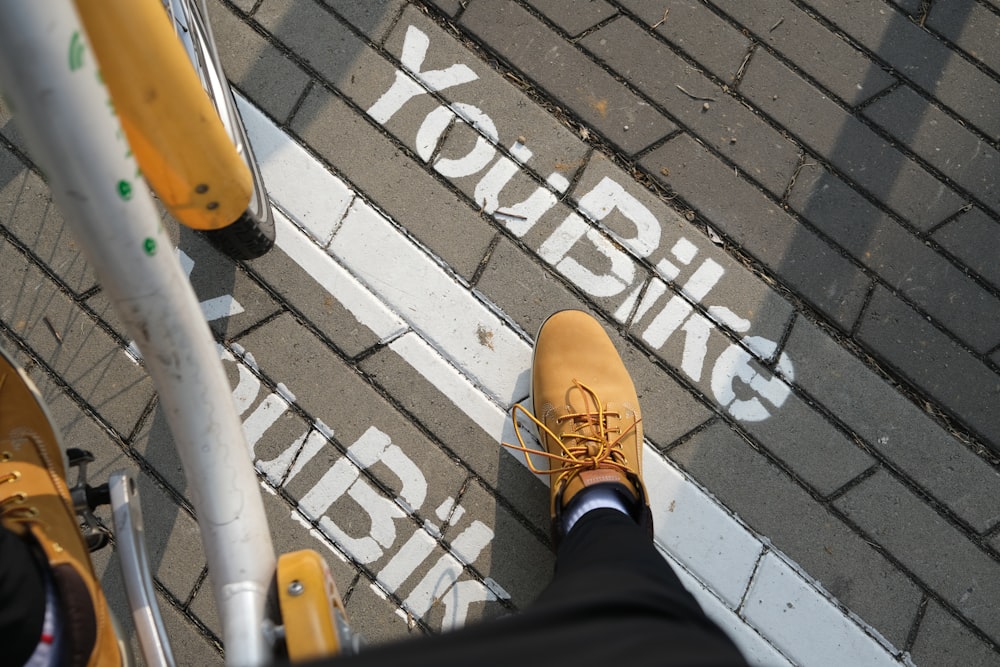 a person standing on a sidewalk with yellow shoes