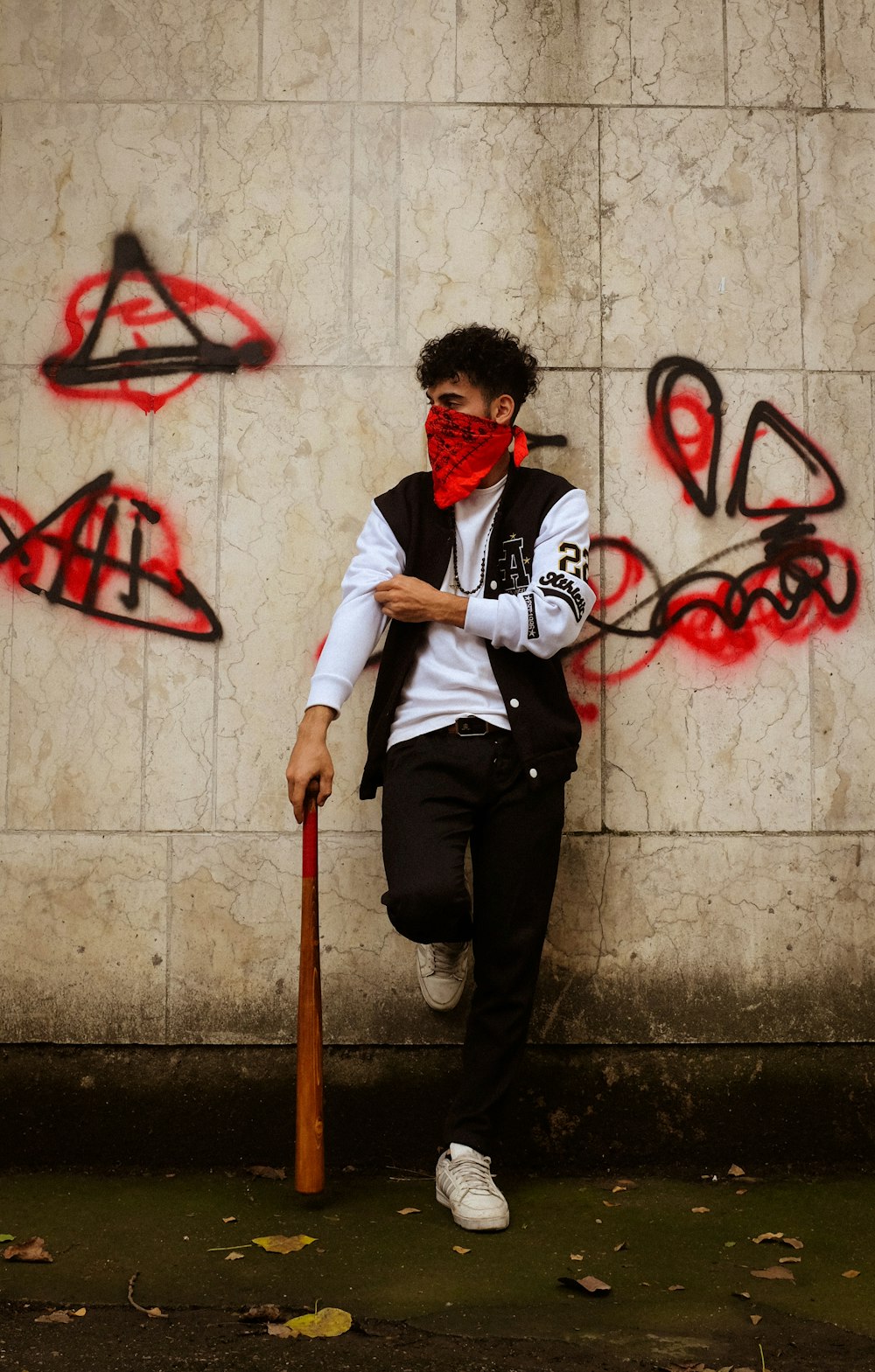 a man with a baseball bat leaning against a wall