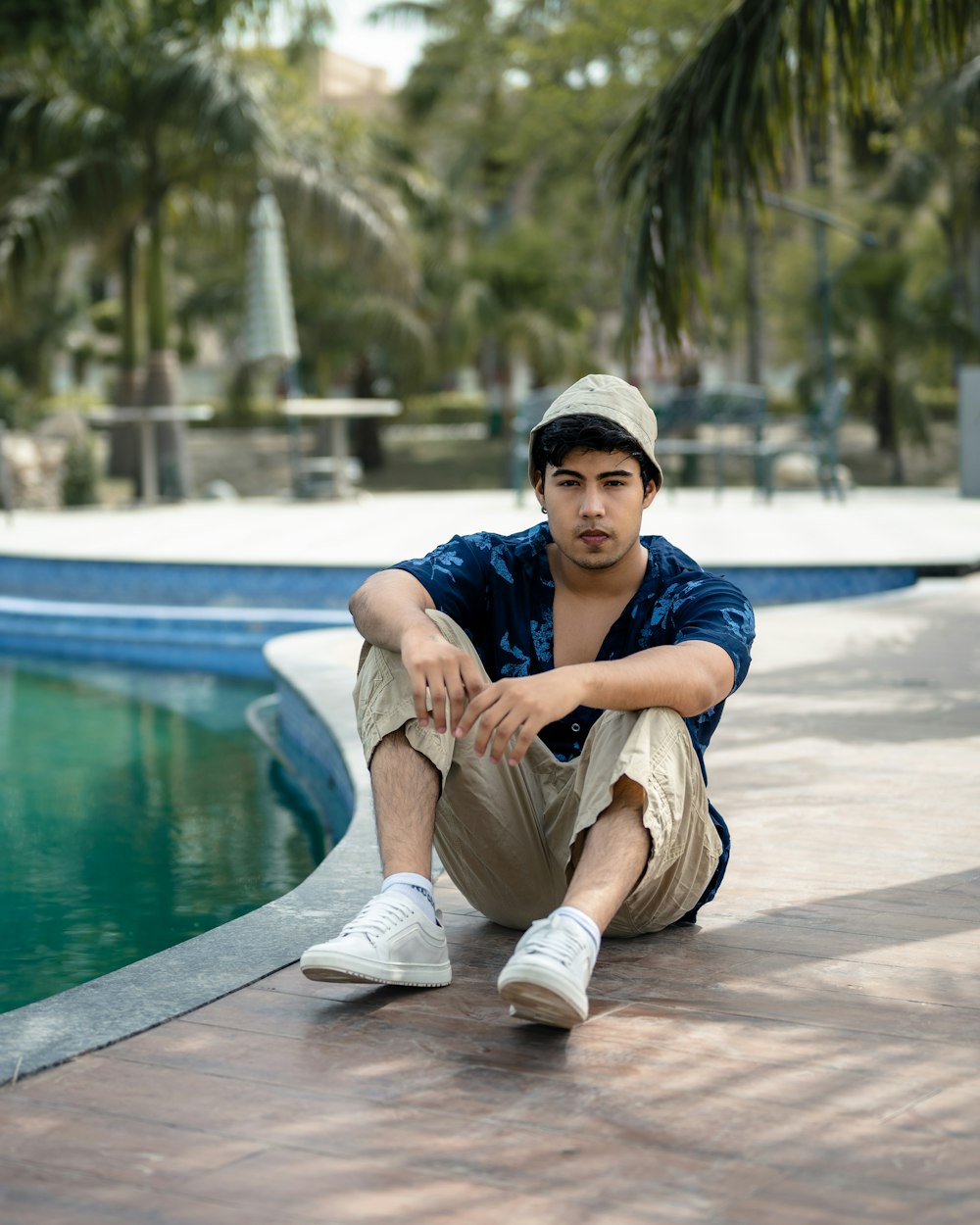 a man sitting on the ground next to a pool