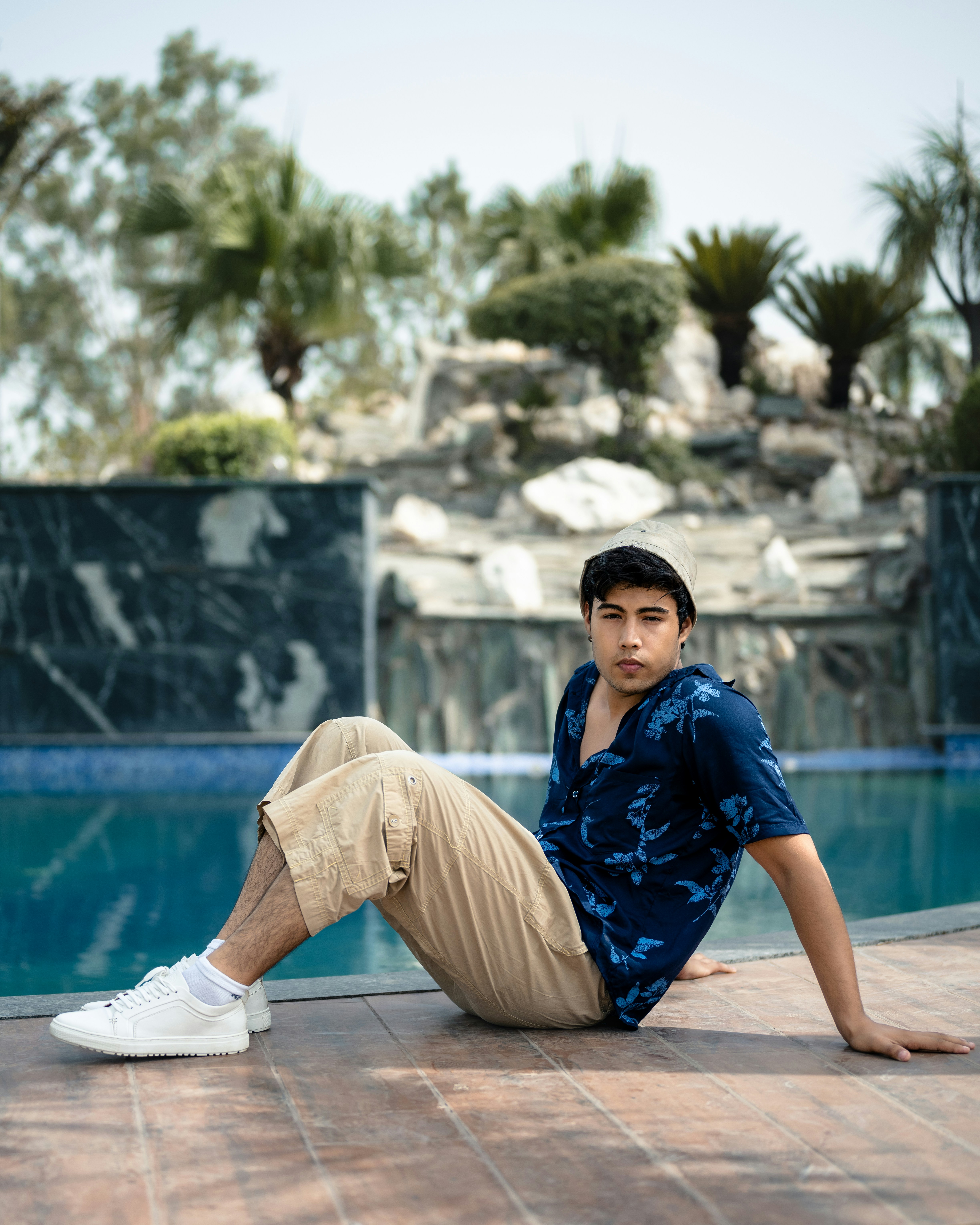 a man sitting on the ground next to a swimming pool