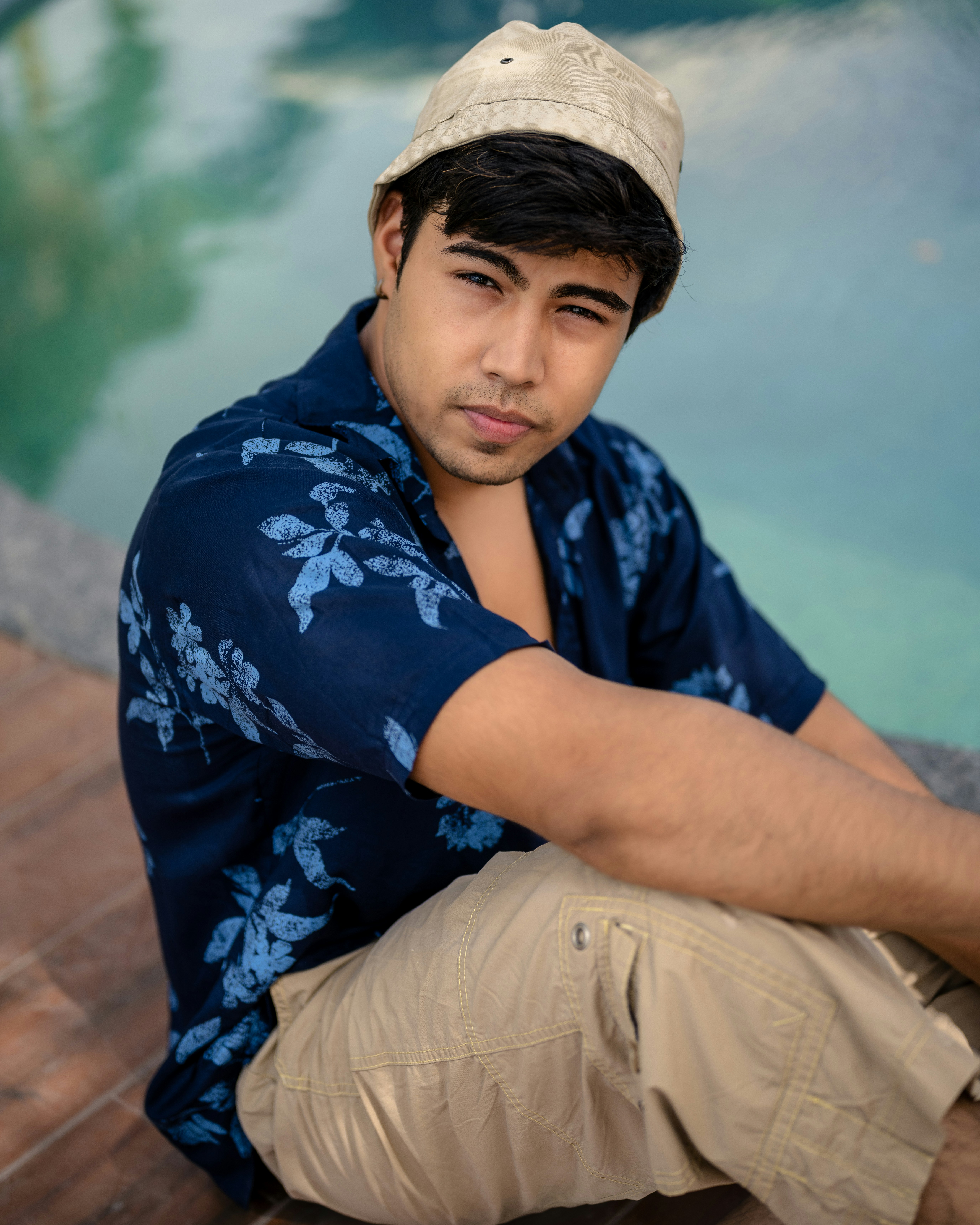 a man sitting on the ground next to a pool
