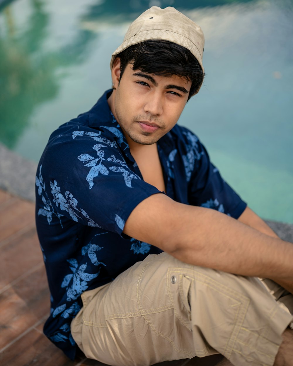 a man sitting on the ground next to a pool