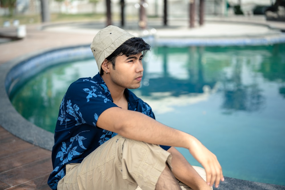 ein Mann sitzt am Rande eines Schwimmbeckens