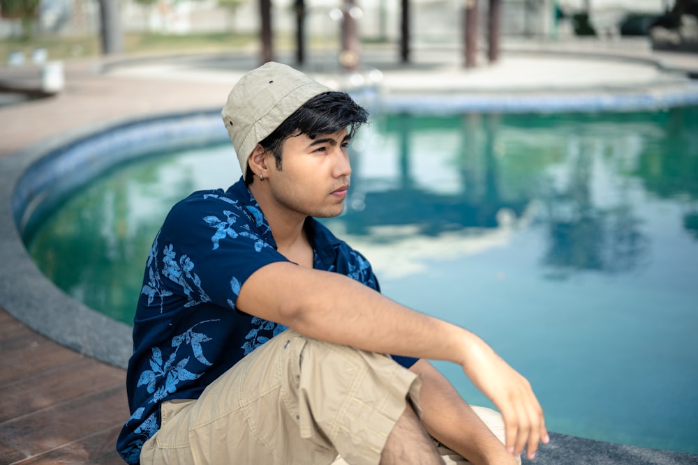 a man sitting on the edge of a swimming pool