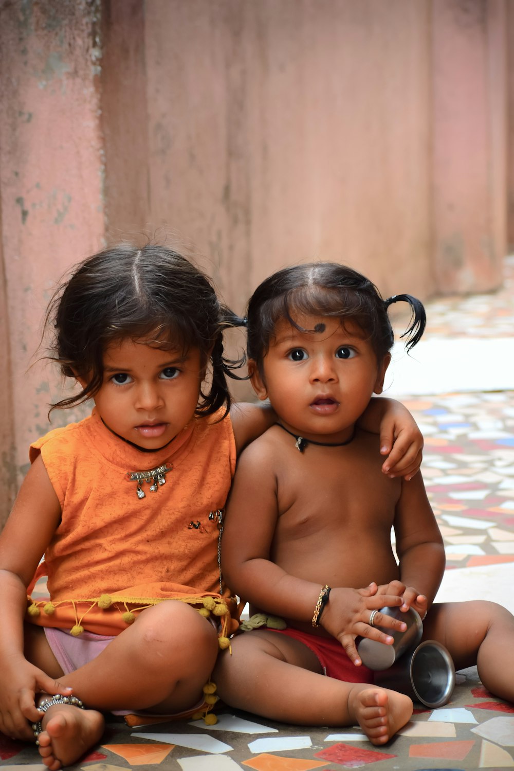 two young children sitting on the ground next to each other