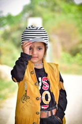 a little girl wearing a yellow jacket and a hat