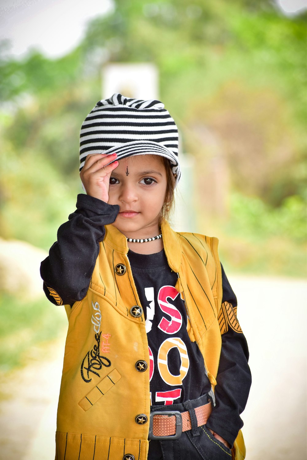 a little girl wearing a yellow jacket and a hat
