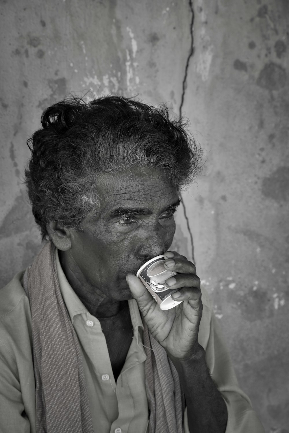a black and white photo of a man drinking something