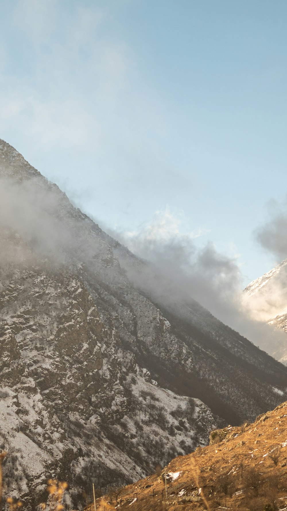 a mountain covered in snow with clouds coming off of it